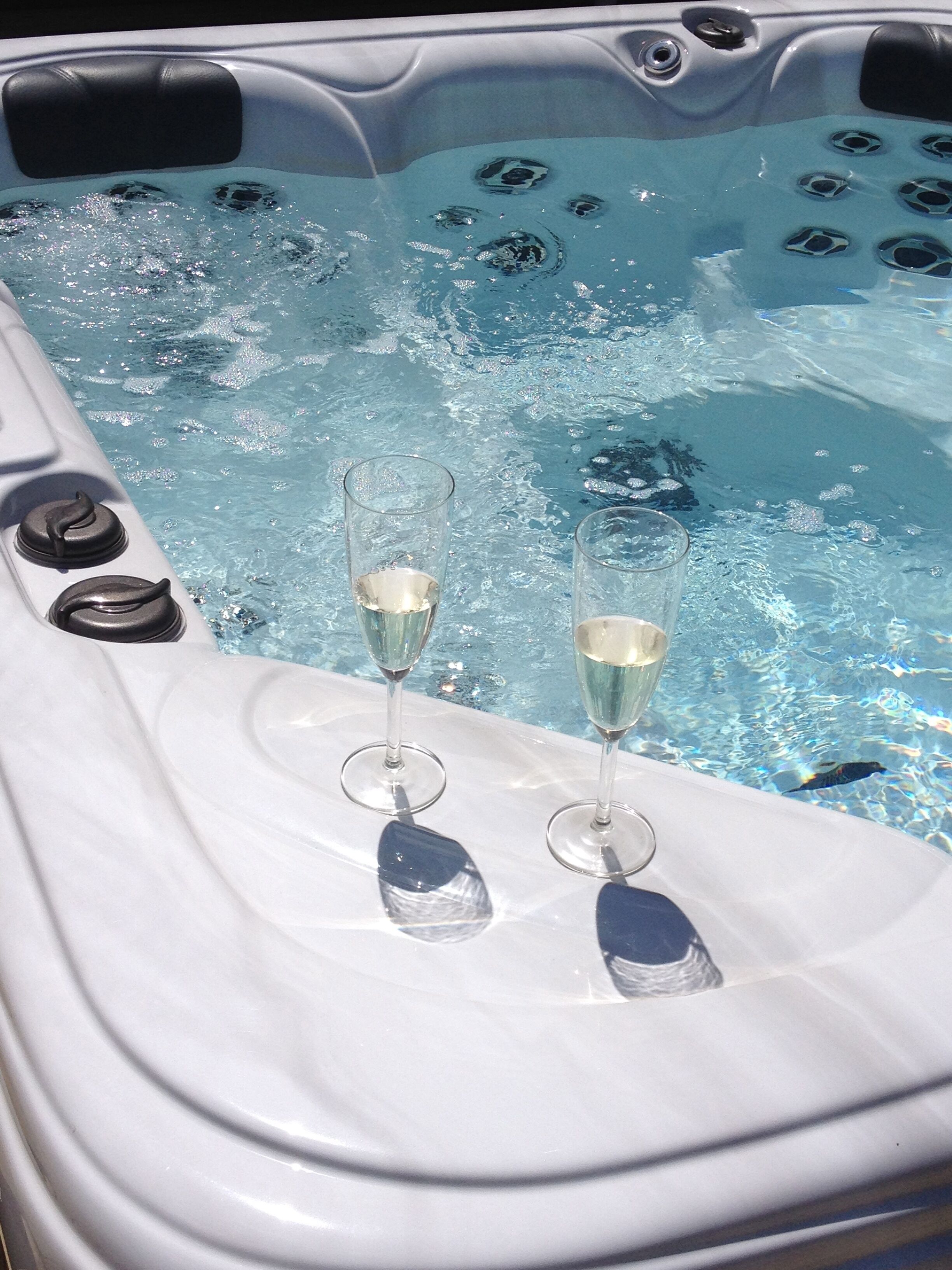 A hot tub with two glasses of champagne.