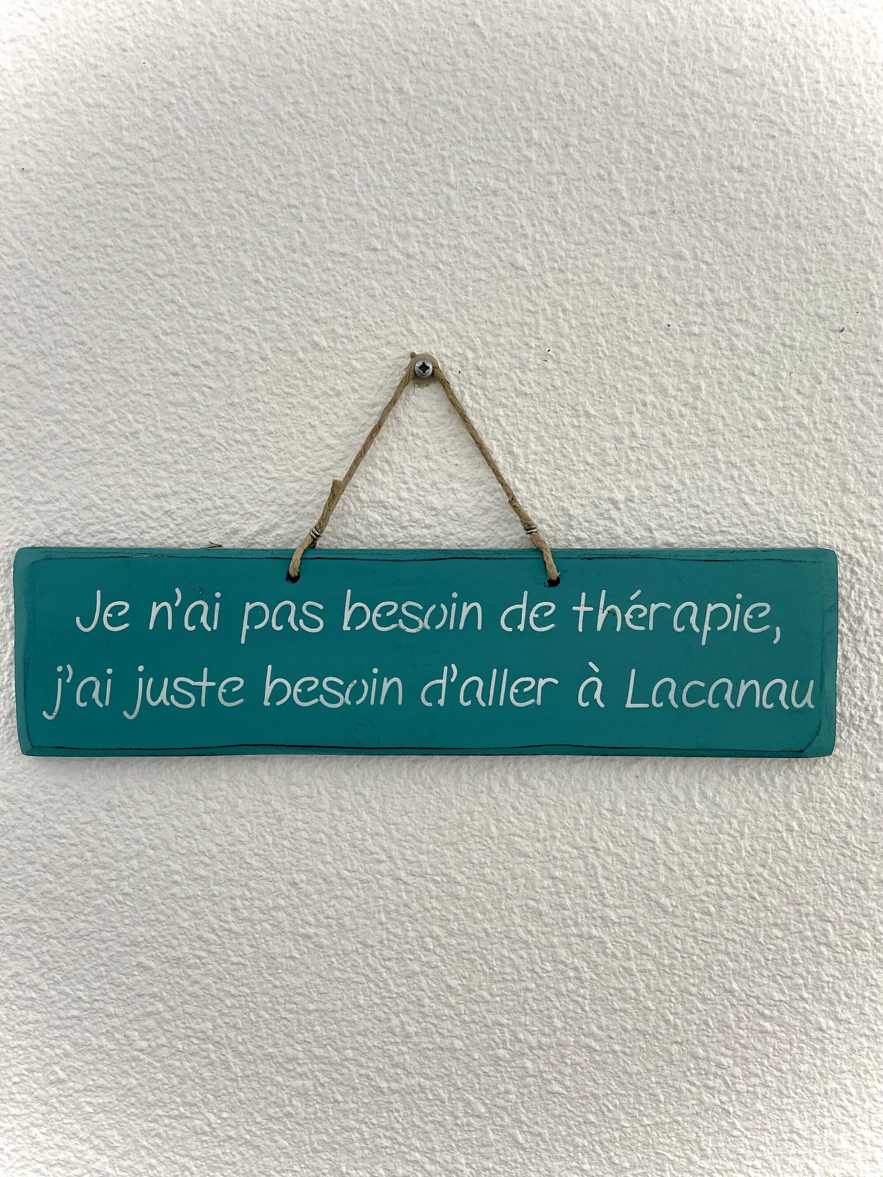 A teal sign with white text on a textured wall.