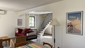 A cozy living room with a sofa, a dining table, and a staircase leading to another level.