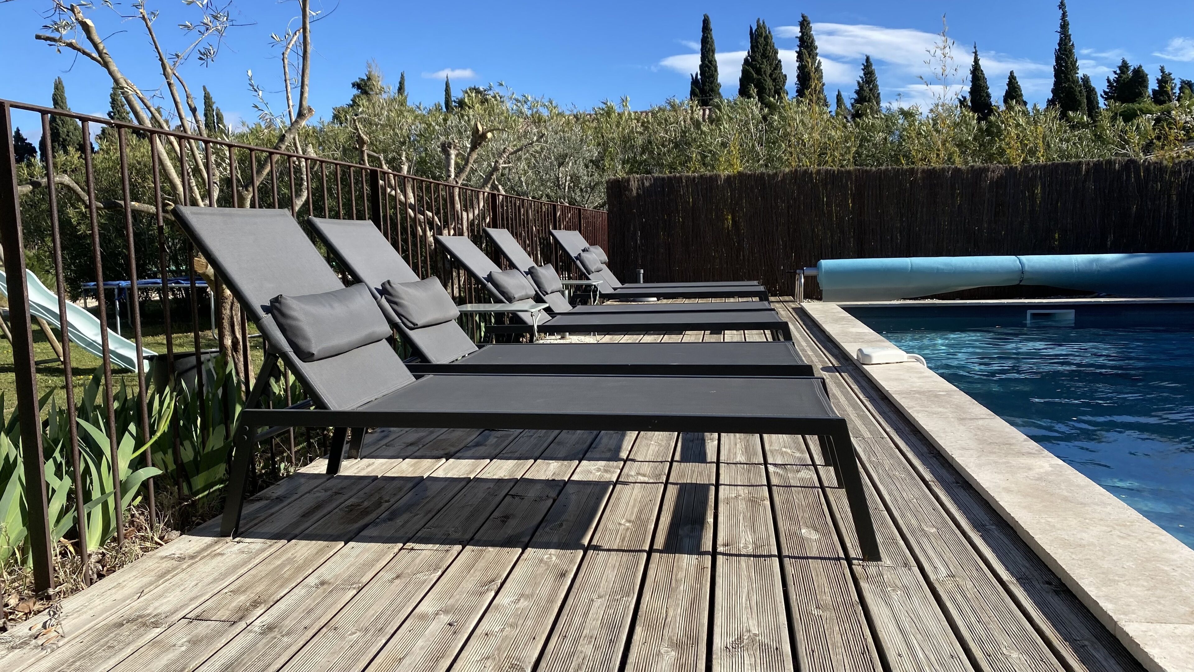 Um deck de madeira com cadeiras de lounge e uma piscina.