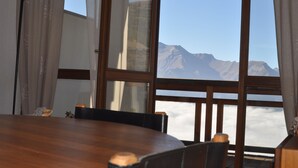 A dining area with a large window overlooking a mountain range. - Charming apartment 40 m2 / 4 p classified 3 *** old district Alpe, magnificent view (Huez)