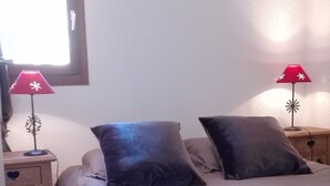 A bedroom with a bed, two nightstands, a window, and two wall-mounted lamps. - Charming apartment 40 m2 / 4 p classified 3 *** old district Alpe, magnificent view (Huez)