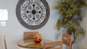 A dining area with a round table, four wooden chairs, and a decorative wall piece. - Ocean Front Condo - 1 Bedroom/bath - Sleeps 4 (Lincoln City)