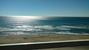 A beach with people walking along the shore and waves crashing onto the sand. - Ocean Front Condo - 1 Bedroom/bath - Sleeps 4 (Lincoln City)