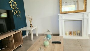 Ein Wohnzimmer mit Couchtisch aus Holz, einem Fernseher, einem weißen Kamin und Dekoelementen.