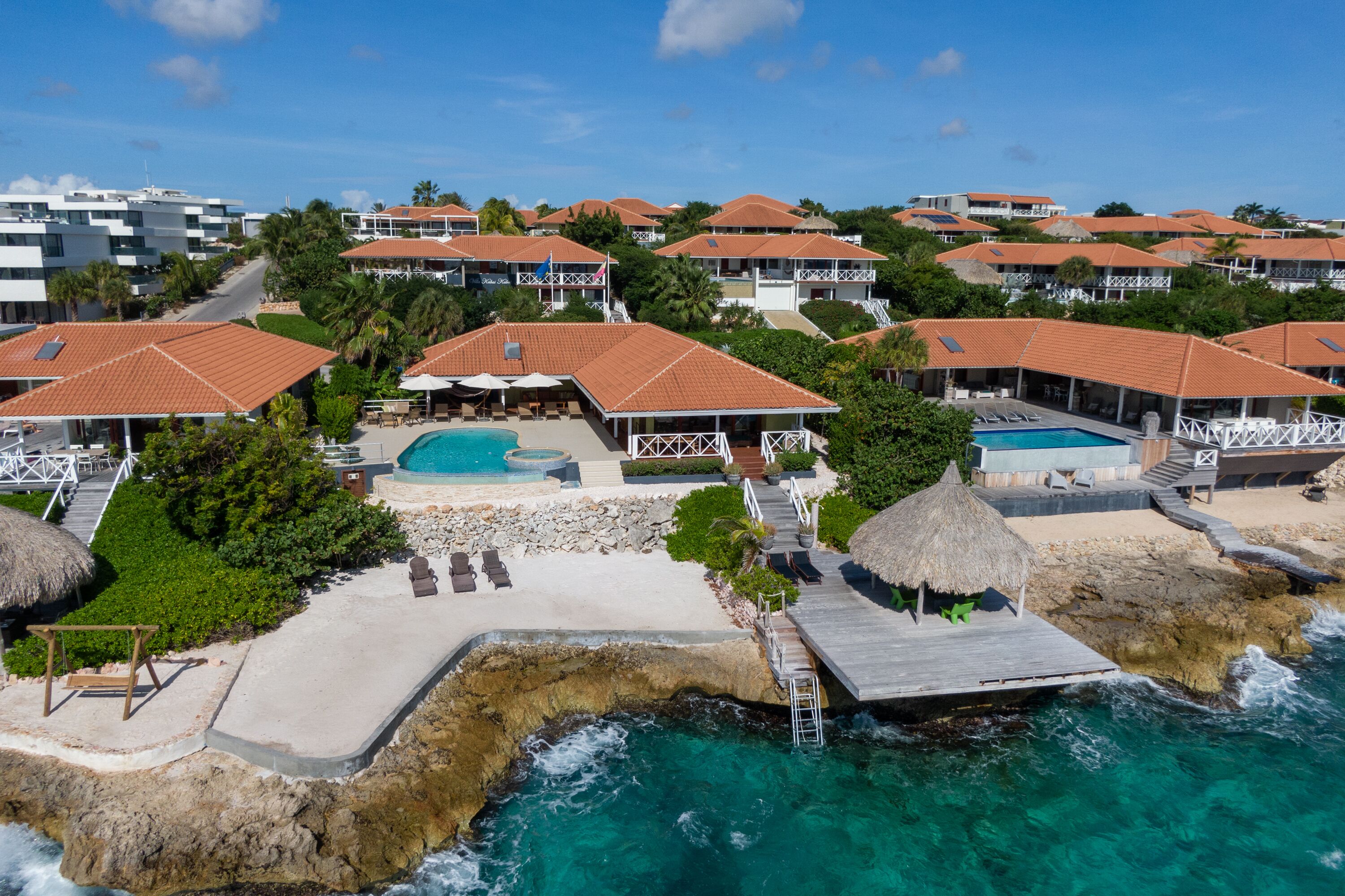 Un resort con diversi edifici, una piscina e un molo che si protende sull'oceano.