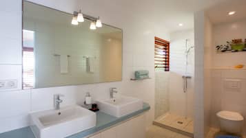 A modern bathroom with two sinks, a large mirror, and a shower area.