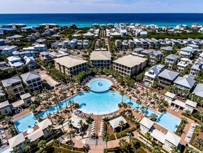 A resort with multiple swimming pools, a central circular pool, and a view of the ocean.