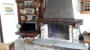 Ein Kamin aus Stein mit hölzernem Sims, einem steinernen Herd und einem Bücherregal voller Bücher und Dekoration.