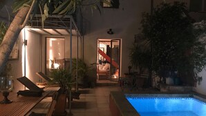 An outdoor pool area with lounge chairs, a small table, and potted plants.