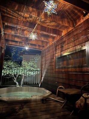 A wooden cabin interior with a hot tub, a wooden table, and a hanging light fixture. - Weekly Discounts! Whitefish Mountain Ski Resort ski in ski out, Luxury Townhouse (Whitefish)