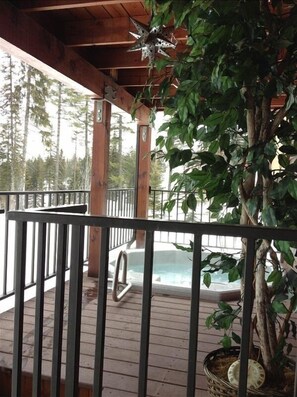 Relax on the deck overlooking a serene forest, where a hot tub awaits.