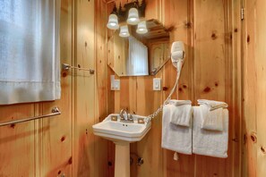 A wooden-paneled bathroom with a sink, mirror, and towel rack.