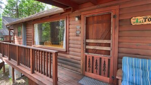 A wooden cabin with a porch, a door with a tree design, and a sign that reads 'TO.'