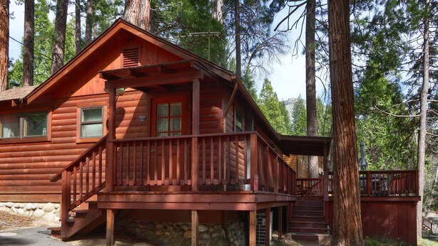 A log cabin with a porch, stone foundation, and a staircase leading to the entrance.
