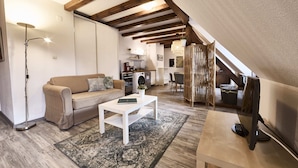 Un espacio tipo loft con sofá, una mesa de centro y una mesa de comedor.