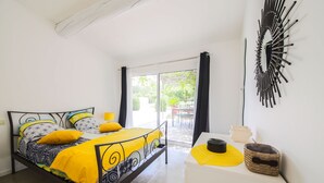 Una camera da letto con un letto, un comodino bianco, una decorazione murale nera e vista attraverso una porta in vetro.