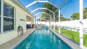 A swimming pool with a covered patio area, a hose, and a small chair. - March openings! Heated pool, 3 + den bdrm luxury, beach vacation gem! (Naples)