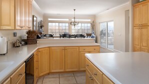 A kitchen with wooden cabinets, a large island, and a view through the windows. - Family Getaway~Hot Tub, Ice Castles & Tubing HS (Midway)