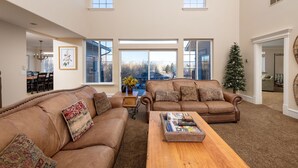A spacious living room with two brown leather sofas, a wooden coffee table, and a large window providing a view of the outdoors. - Family Getaway~Hot Tub, Ice Castles & Tubing HS (Midway)
