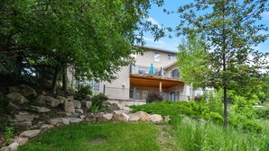 A two-story building with a balcony, surrounded by greenery and a stone wall. - Family Getaway~Hot Tub, Ice Castles & Tubing HS (Midway)