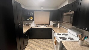 Una cocina compacta con armarios oscuros, una isla central, una estufa y un microondas.