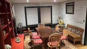 Un comedor con mesa y sillas de madera, un banco rojo y una estantería.