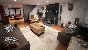 Una sala de estar moderna con chimenea, sofás de cuero, una mesa de centro de madera y un televisor montado en la pared.