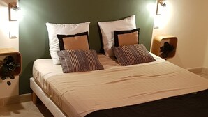 A neatly made bed with a headboard, two bedside tables, and a wall-mounted decorative item.