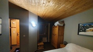 Ein Schlafzimmer mit Holzboden, einem Bett mit weißer Bettdecke, einem Kleiderschrank und einem Bild an der Wand.