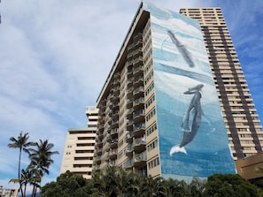 Een hoog gebouw met een groot muurschildering van een walvis.