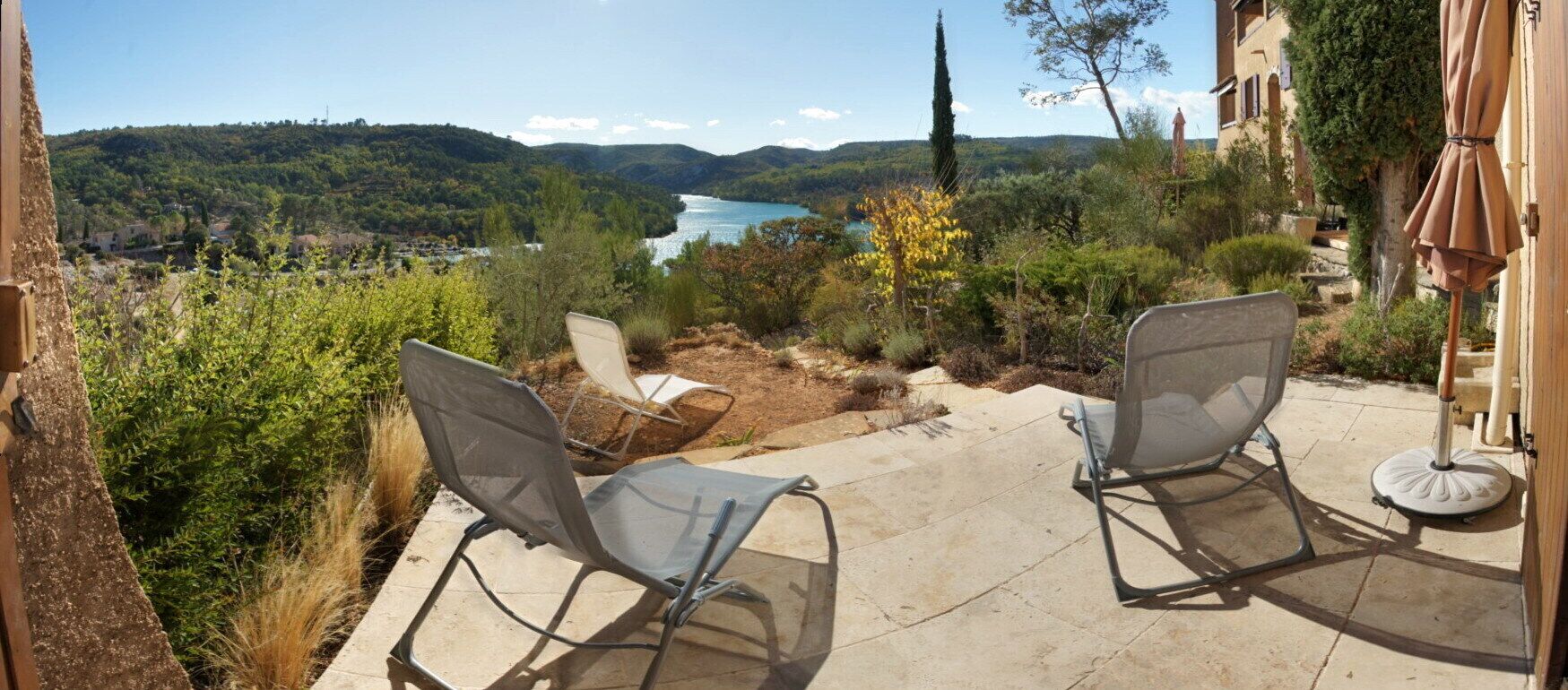Un patio con dos sillas que da a una vista panorámica de un lago y colinas.