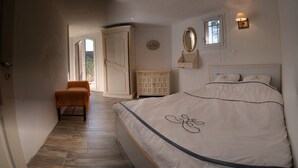 A bedroom with a bed, a chair, a dresser, a mirror, and a window. - Apartment for 6 in Esparron-de-Verdon, with a wonderful lake view (Esparron-De-Verdon)