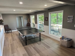 A ping pong table in a room with large windows, a chair, and a wall with motivational quotes.