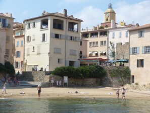 A coastal town with buildings, a beach, and a tower.