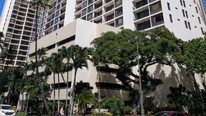A tall, modern building with multiple floors, large windows, and balconies.
