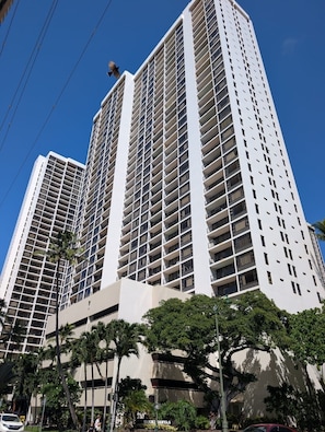 A tall, modern building with multiple floors, large windows, and balconies.