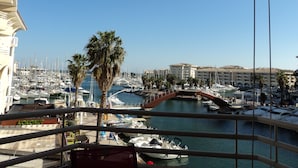 A marina with boats docked, palm trees, and a building in the background. - LOCATED APARTMENT IN PORT FREJUS (Fréjus)