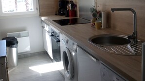 A modern kitchen with white cabinets, a built-in washing machine, a coffee maker, and a sink. - LOCATED APARTMENT IN PORT FREJUS (Fréjus)