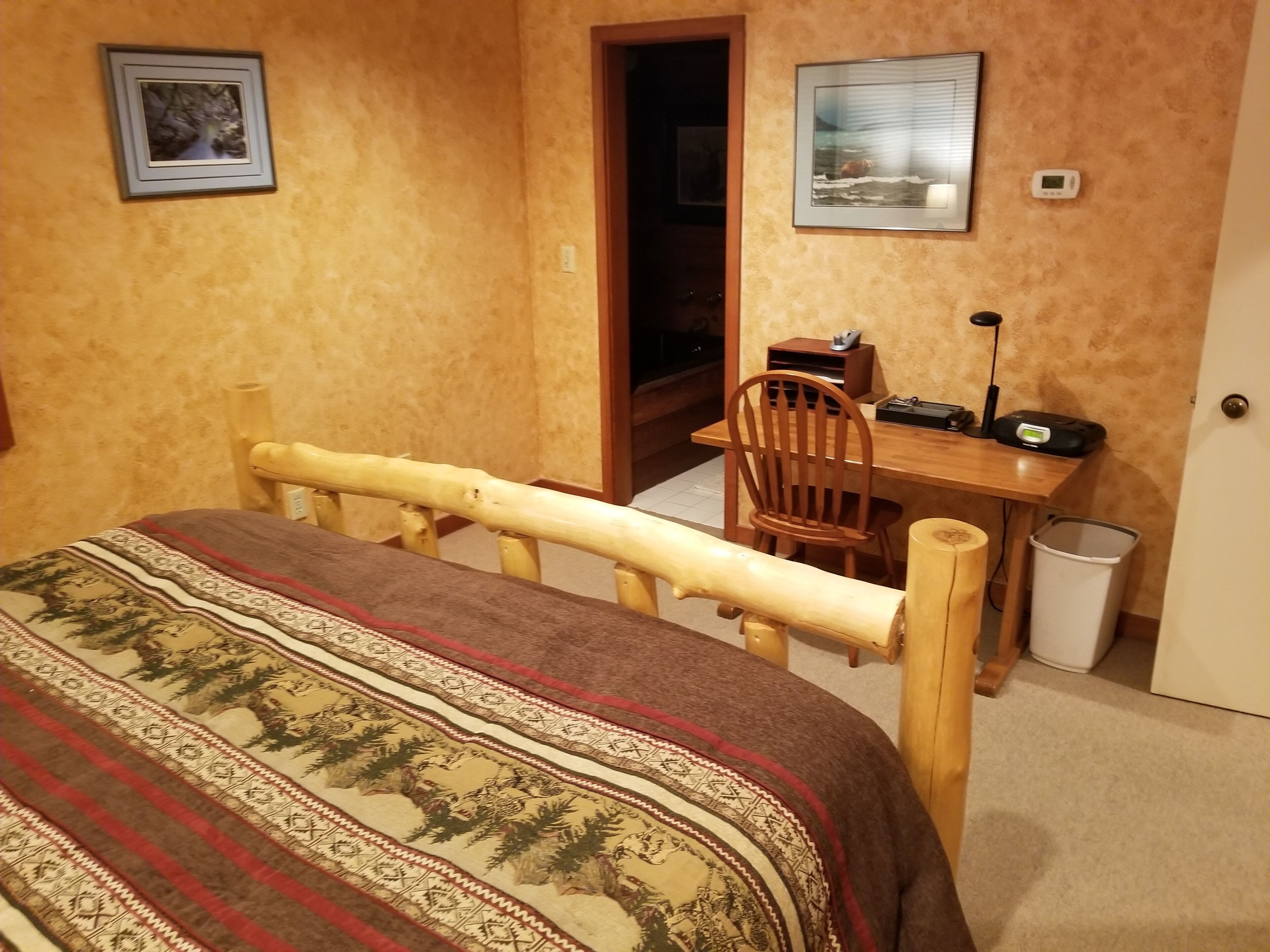 A bedroom with a bed, a wooden desk, and a chair.