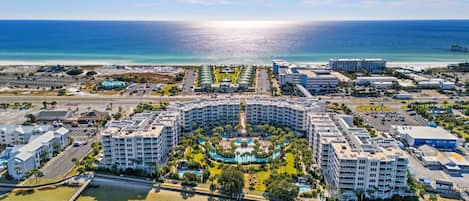 Un resort con piscina centrale, diversi edifici e spiaggia.