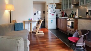 A compact living space with a kitchenette, a dining area, and a sofa with a patterned cushion. - Spacious, light-filled 57m2 character apartment overlooking courtyard ideal for families (Paris)