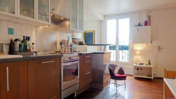 A kitchen with wooden cabinets, a stove, and a window with a view. - Spacious, light-filled 57m2 character apartment overlooking courtyard ideal for families (Paris)
