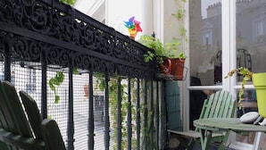A balcony with a wrought iron fence, two green chairs, and potted plants. - Spacious, light-filled 57m2 character apartment overlooking courtyard ideal for families (Paris)