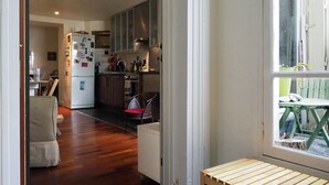 A compact kitchen with wooden cabinets, a refrigerator, and a dining area with a bench and table. - Spacious, light-filled 57m2 character apartment overlooking courtyard ideal for families (Paris)
