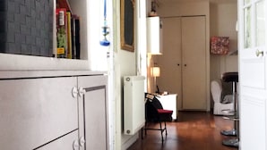 A narrow hallway with a herringbone wooden floor, a white cabinet with drawers, and a desk with a chair. - Spacious, light-filled 57m2 character apartment overlooking courtyard ideal for families (Paris)