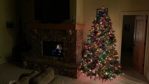 A cozy living room with a stone fireplace, a Christmas tree, and a television mounted above it. - Ski, Mountains, Lake: 5 BR Vacation House at Wolf Creek Ut, Many Amenities (eden)