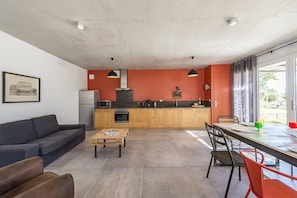 A modern kitchen with wooden cabinets, a dining area with a table and chairs, and a sofa.