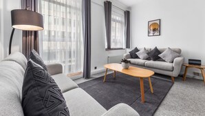 A modern living room with a grey sofa, a wooden coffee table, and a grey rug.