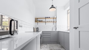 A modern kitchen with white cabinetry, a marble-tiled floor, and a built-in oven.